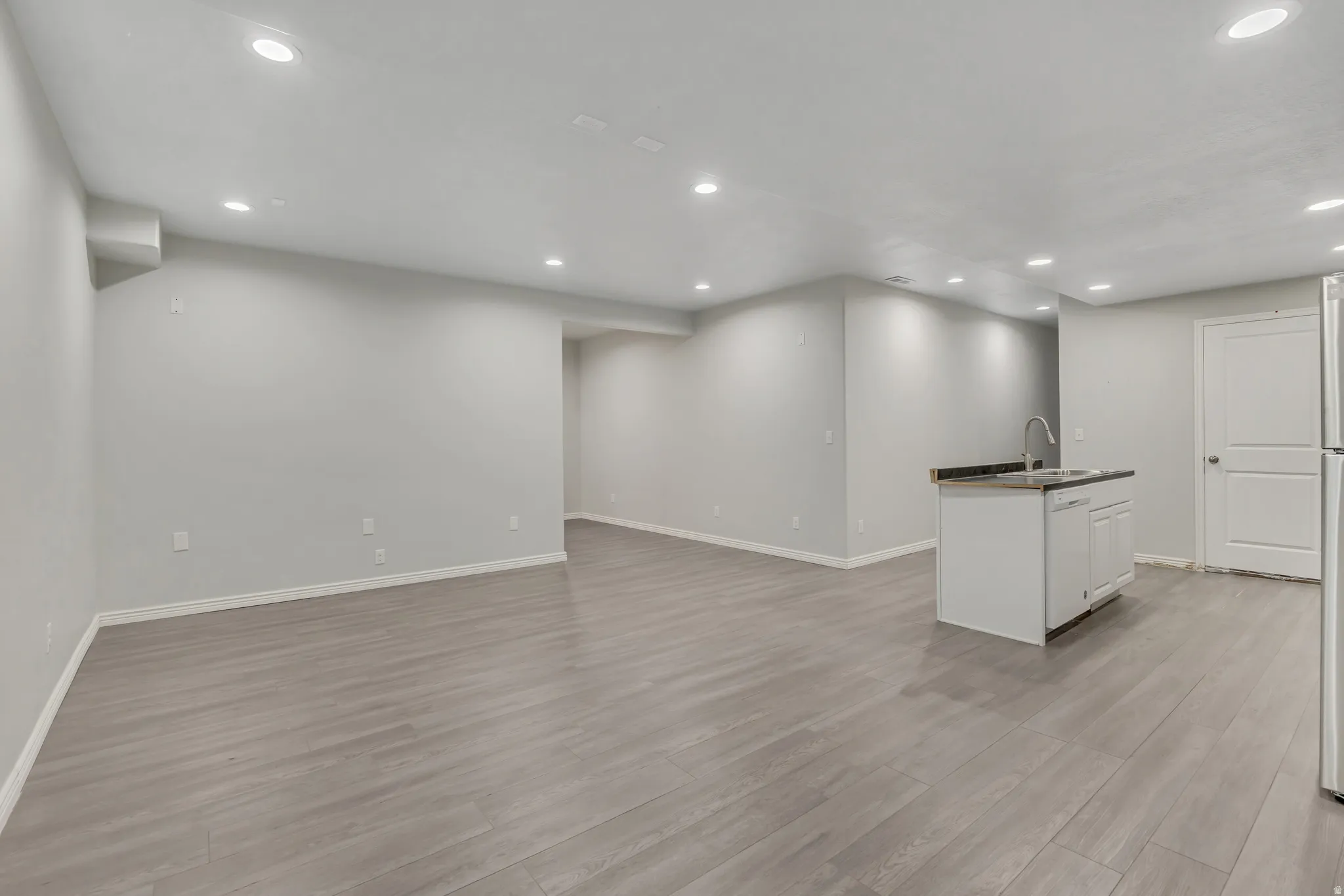 Open-concept living area featuring wood-finish flooring, recessed lighting, and light-toned walls
