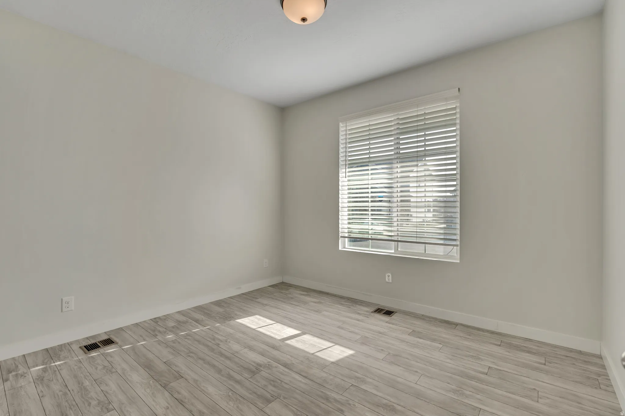 Room featuring wood-finish flooring, neutral wall tones, and a window with horizontal blinds