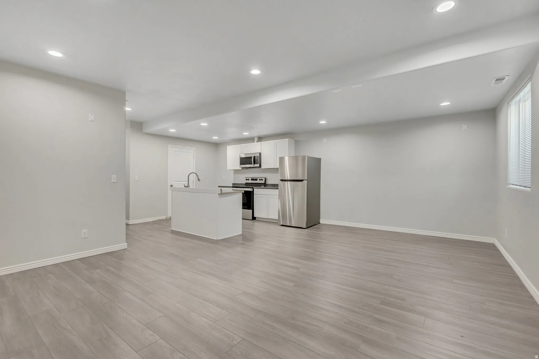 Open-concept living area featuring wood-finish flooring, recessed lighting, and light gray walls