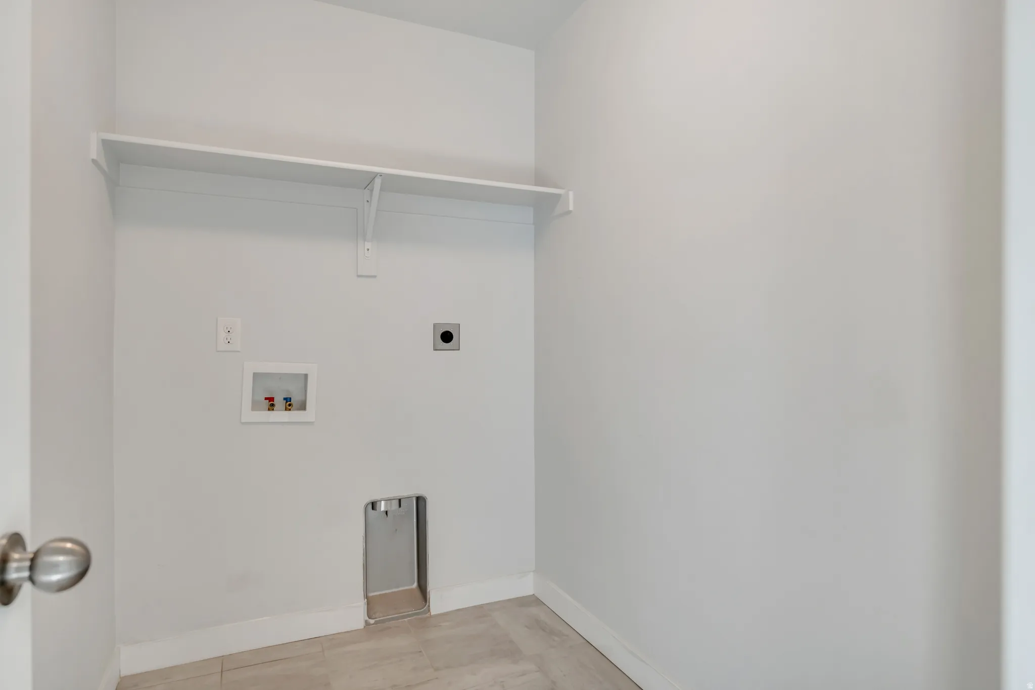 Dedicated utility area featuring a wall-mounted shelf, light-toned wall paint, and tiled flooring