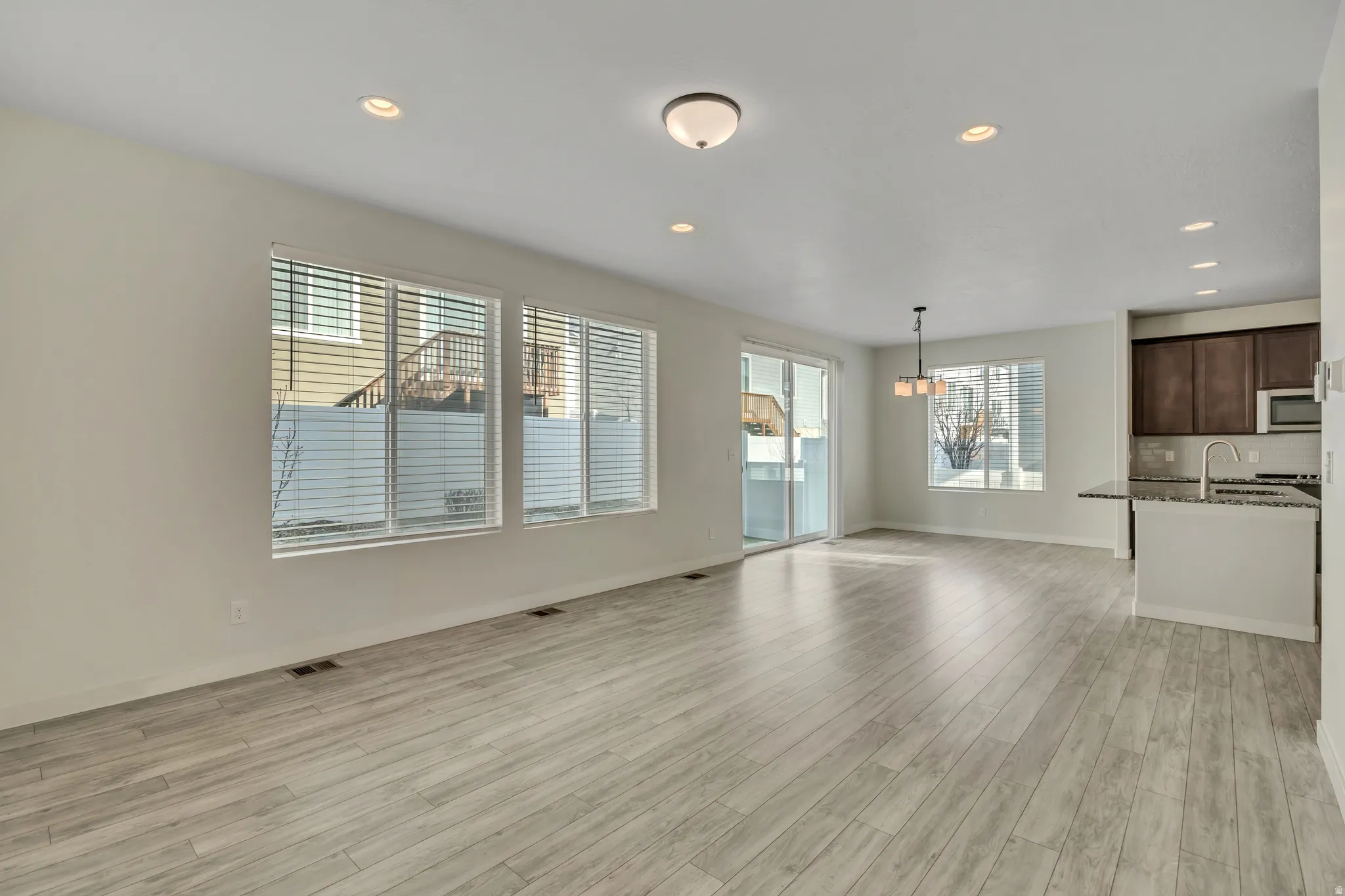 Open-concept living area with wood-finish flooring, recessed lighting, and multiple windows