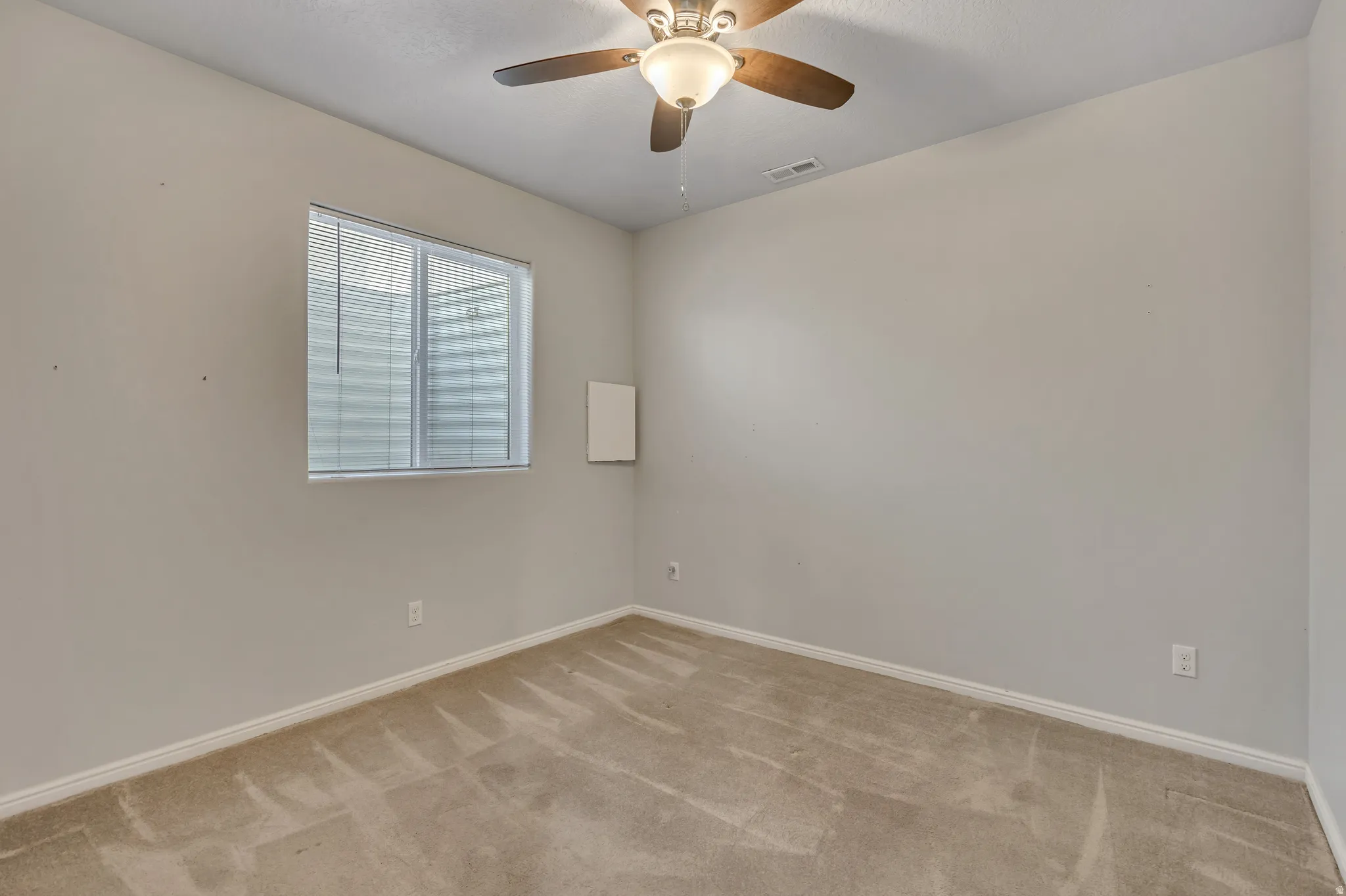 Carpeted room featuring a ceiling fan with integrated lighting, a window with horizontal blinds, and neutral wall tones