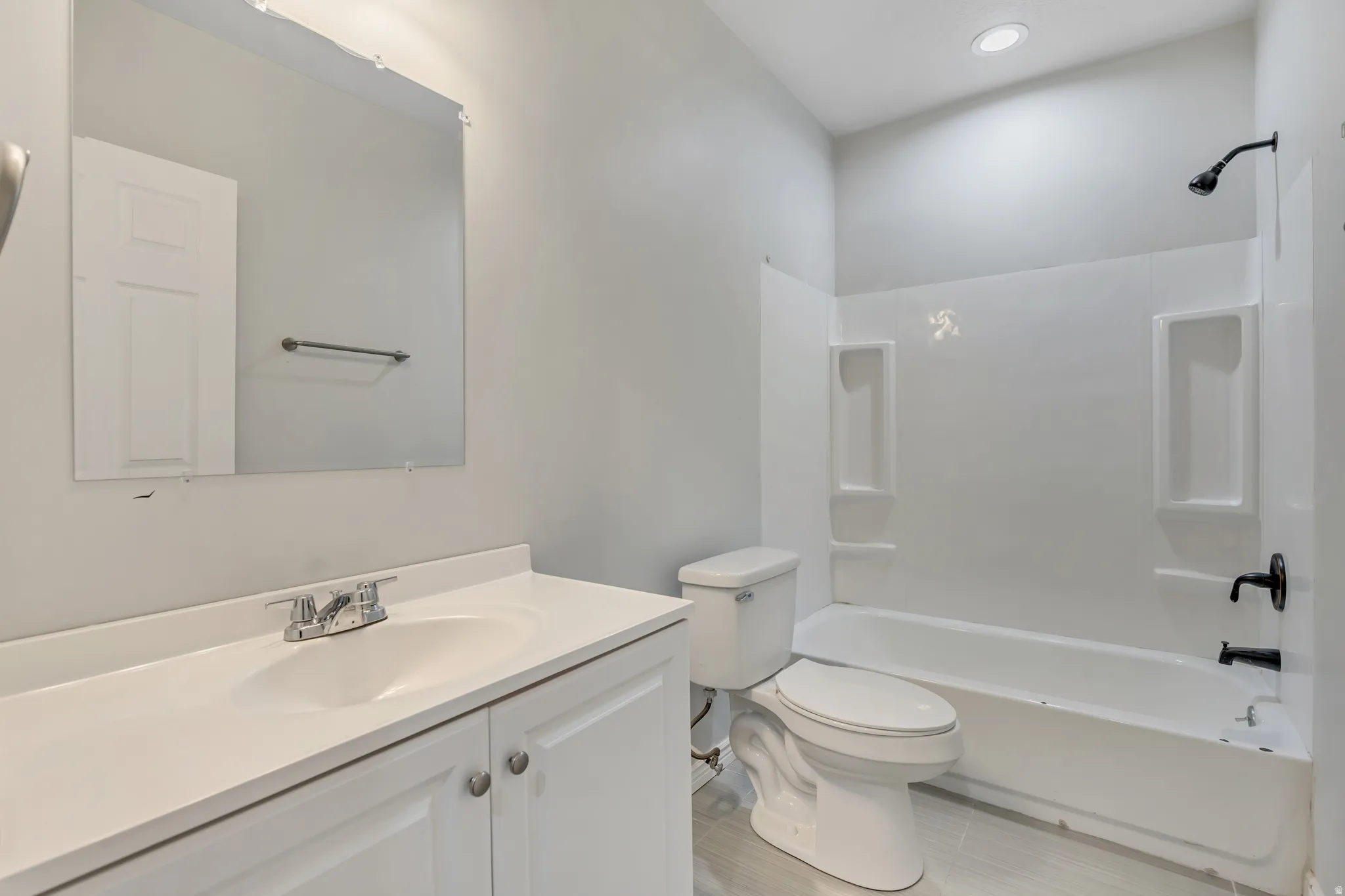 Bathroom featuring a white vanity with integrated sink, chrome faucet, and a wall-mounted mirror