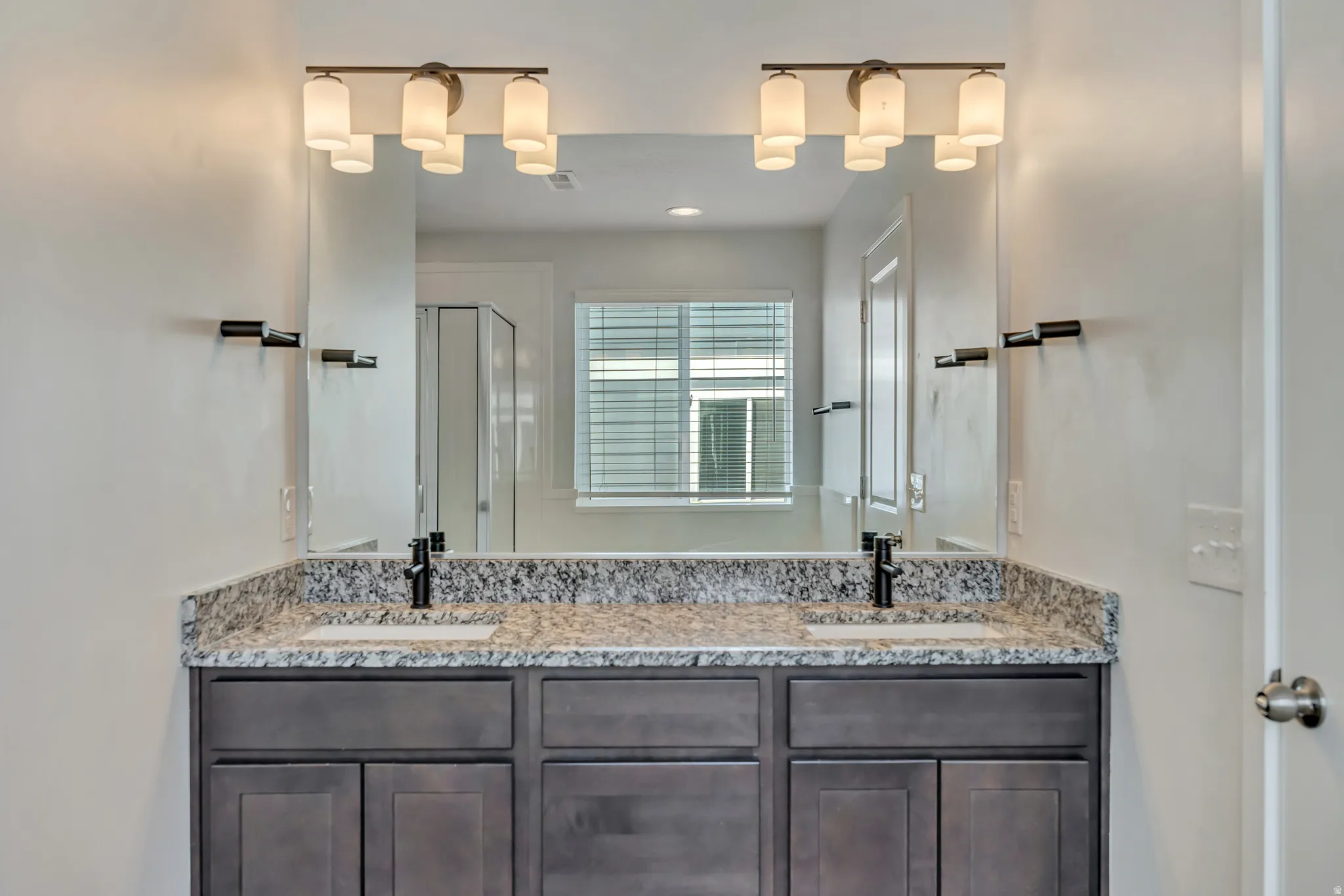 Dual vanity featuring a speckled countertop, undermount sinks, and dark wood-finish cabinetry