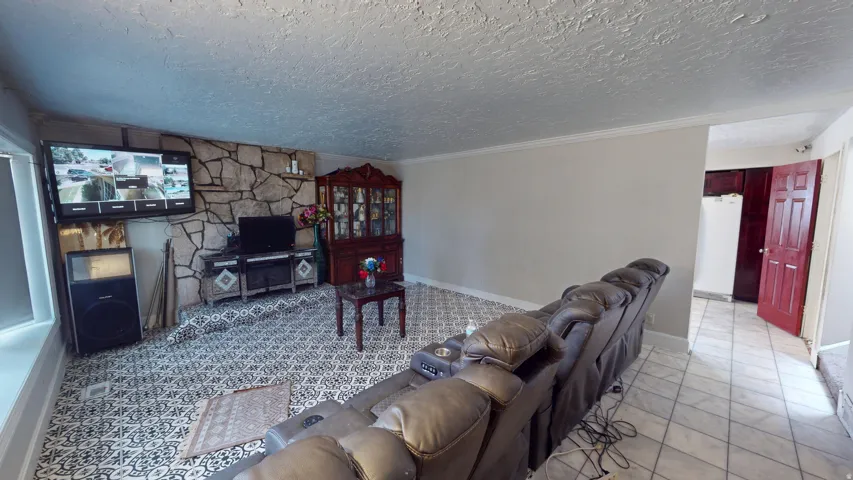 Living area featuring a stone accent wall, patterned floor tile, and a white ceiling with textured finish
