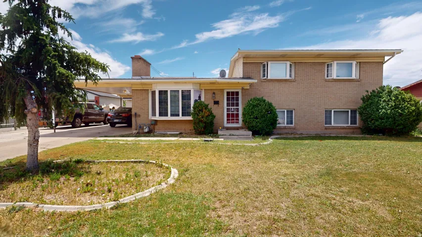 Brick exterior residence featuring a carport, multiple windows, and a front lawn with established landscaping