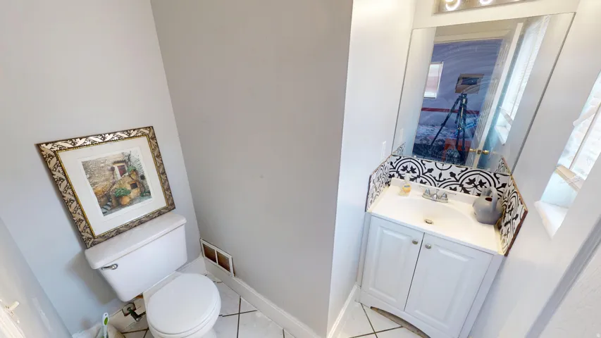 White vanity with built-in sink, chrome fixtures, and a black-and-white patterned tile backsplash