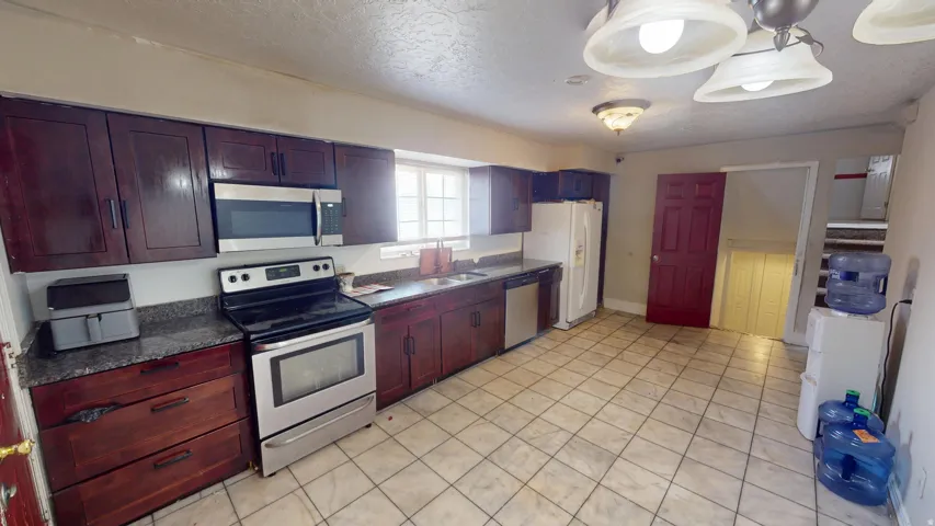 Kitchen featuring dark wood cabinetry, stainless steel appliances, and mottled gray countertops