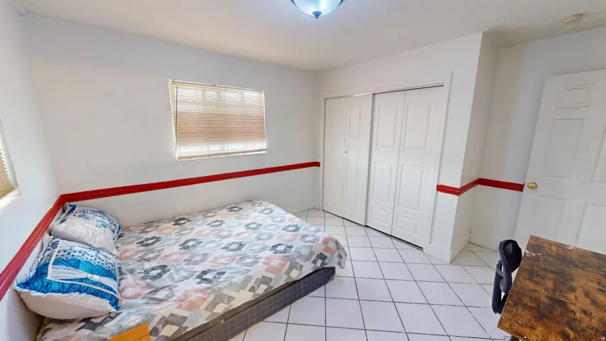 Spacious room featuring white tile flooring and white walls with a red accent band