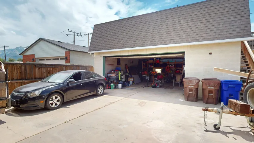 Detached garage structure featuring a shingled roof, light-toned exterior, and an open garage door