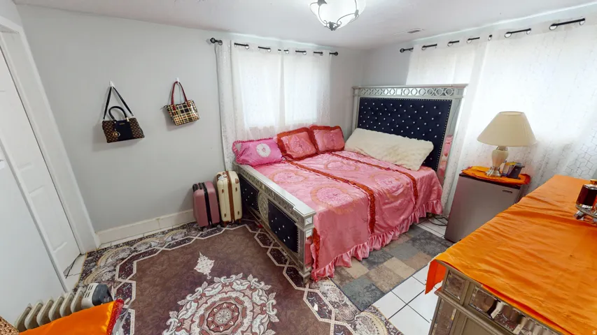 Bedroom with light gray walls, white baseboards, and a patterned area rug