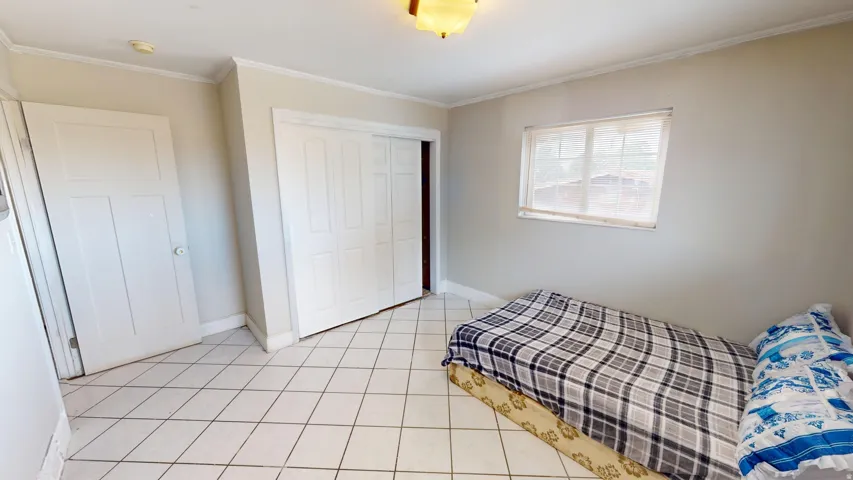 Room featuring white tile flooring, a window with natural light, and sliding closet doors