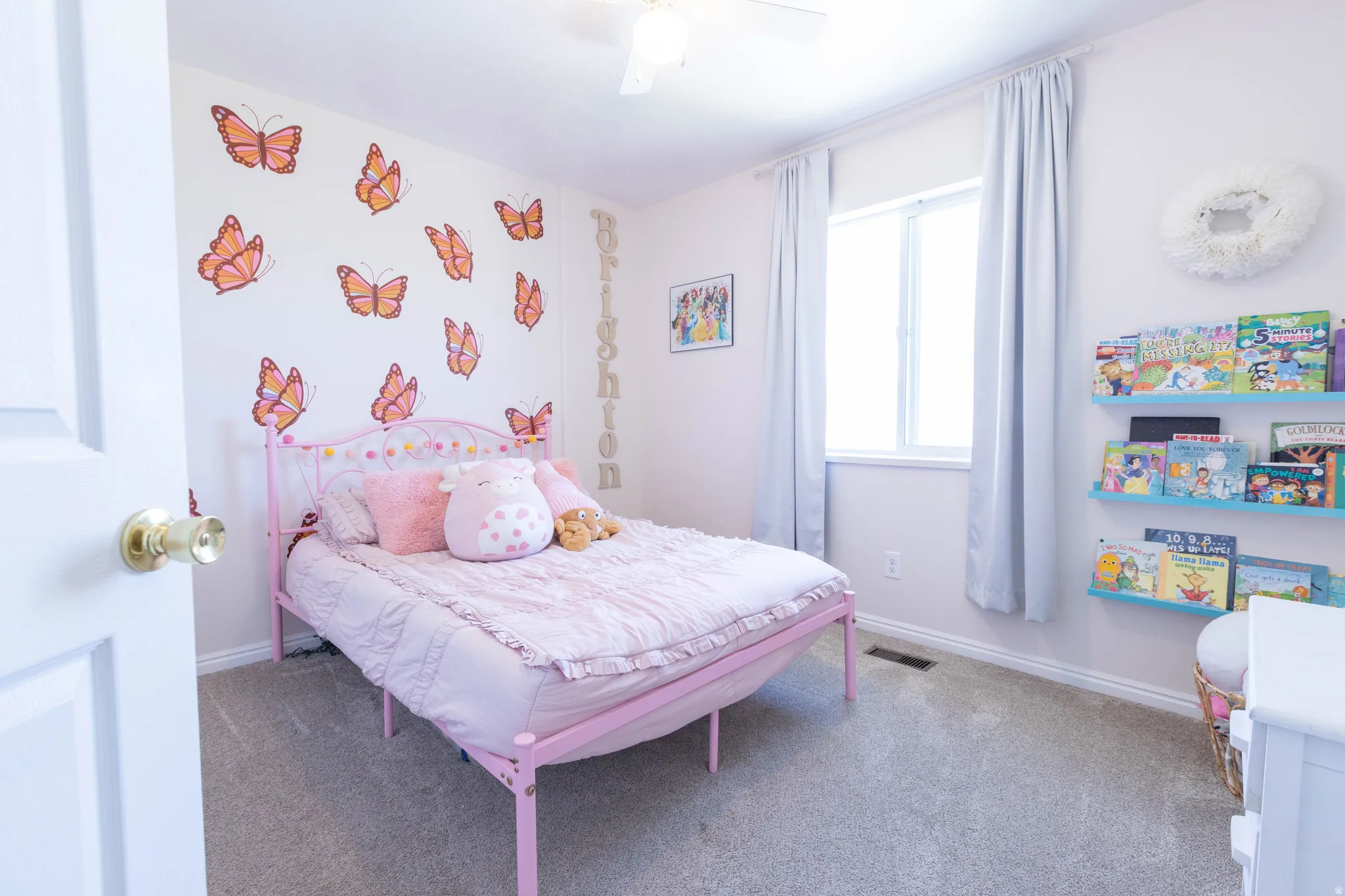 Bedroom featuring light-colored walls, a single window with drapes, built-in shelving, and carpeted flooring