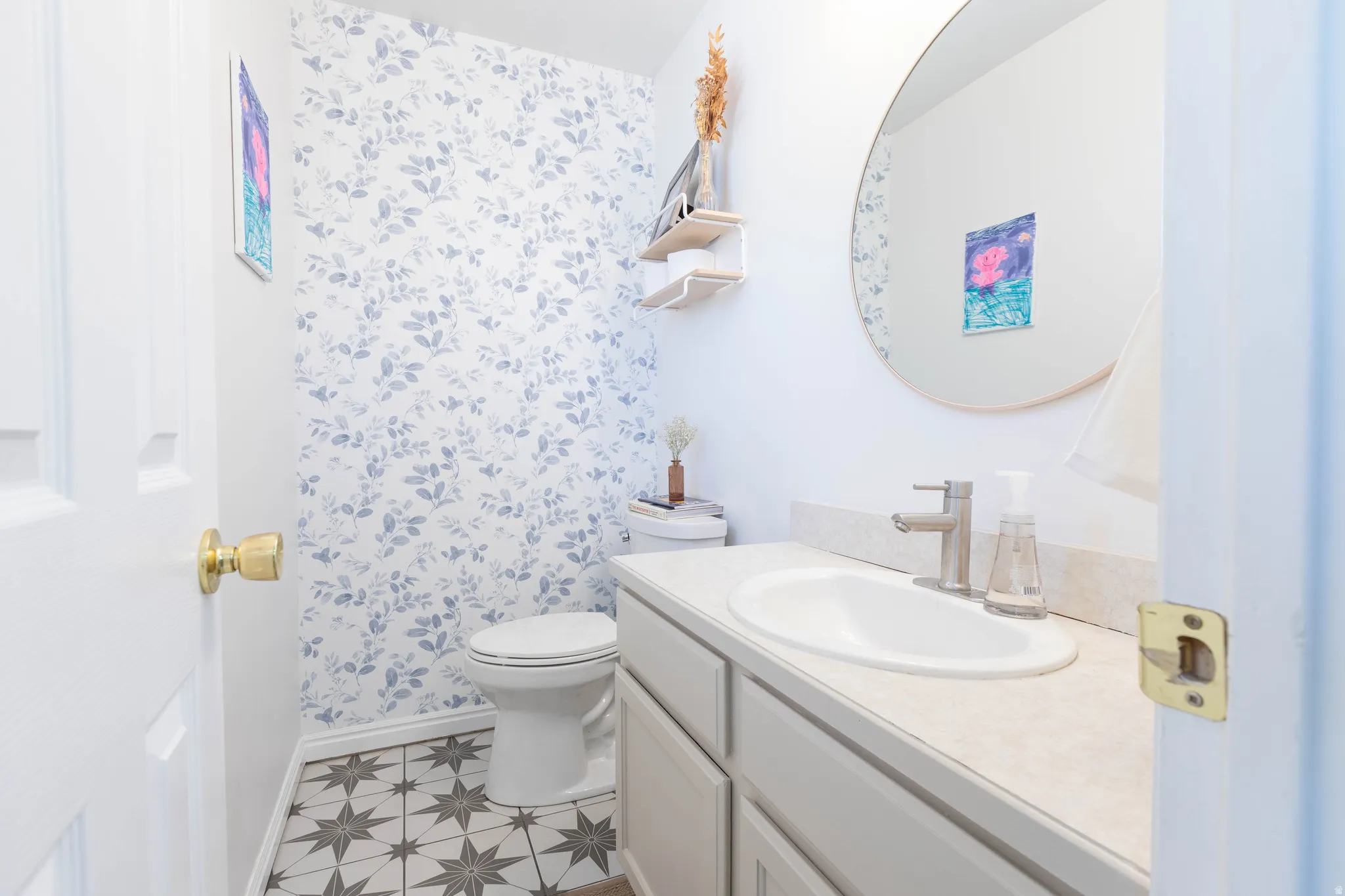 Powder room featuring a single vanity with an integrated sink, patterned floor tile, and a decorative accent wall