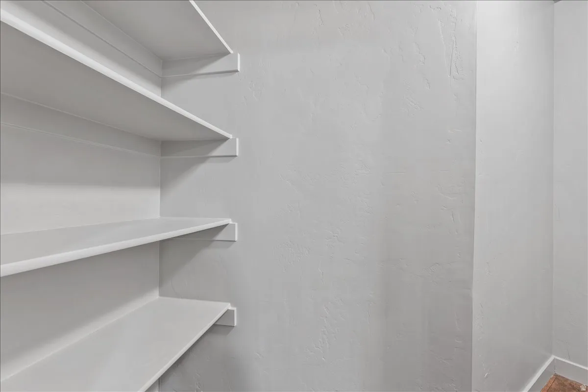 Built-in shelving unit with multiple white shelves against a textured wall
