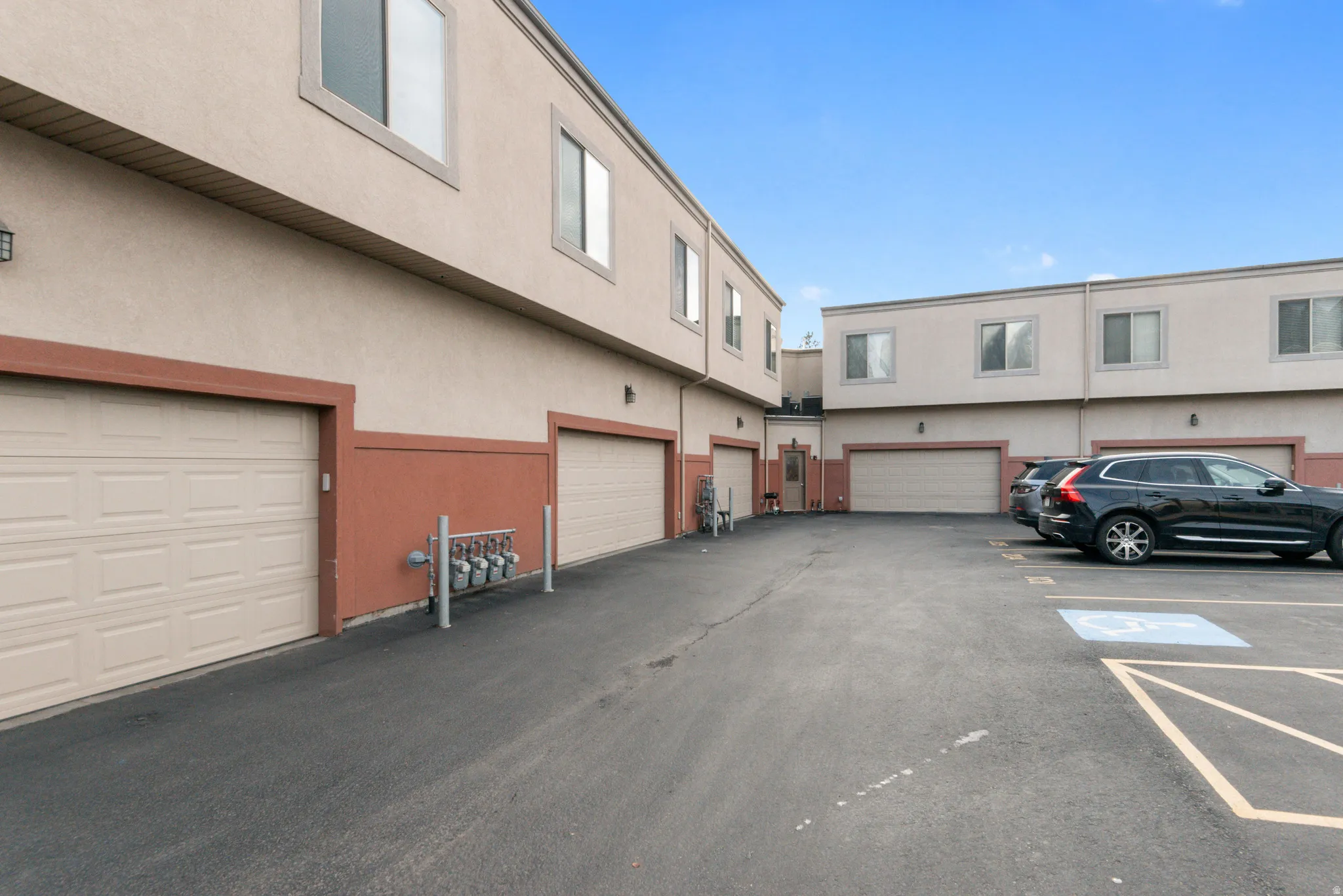 Multi-level stucco exterior building with multiple single-car garage bays and paved parking areas