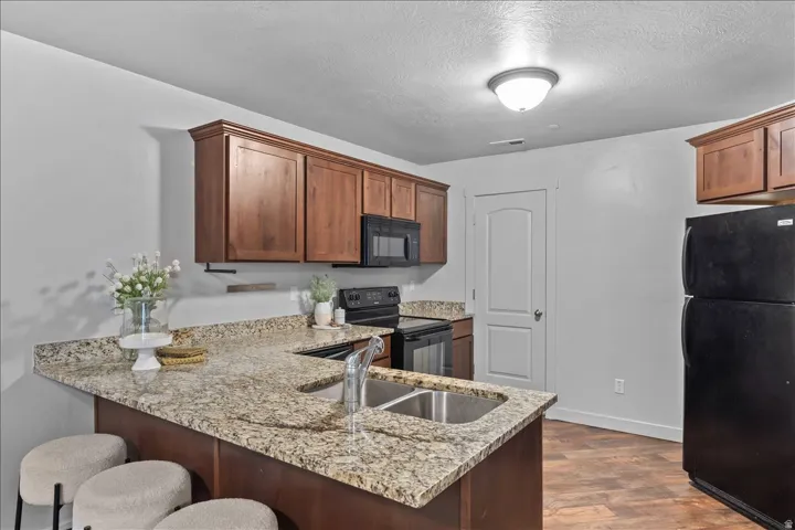 Kitchen featuring granite-style countertops, wood cabinetry, and stainless steel sink
