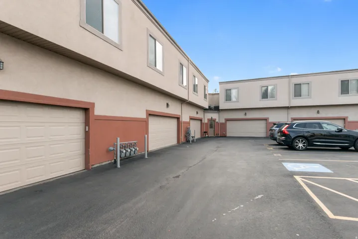 Multi-level stucco exterior building with multiple single-car garage bays and paved parking areas