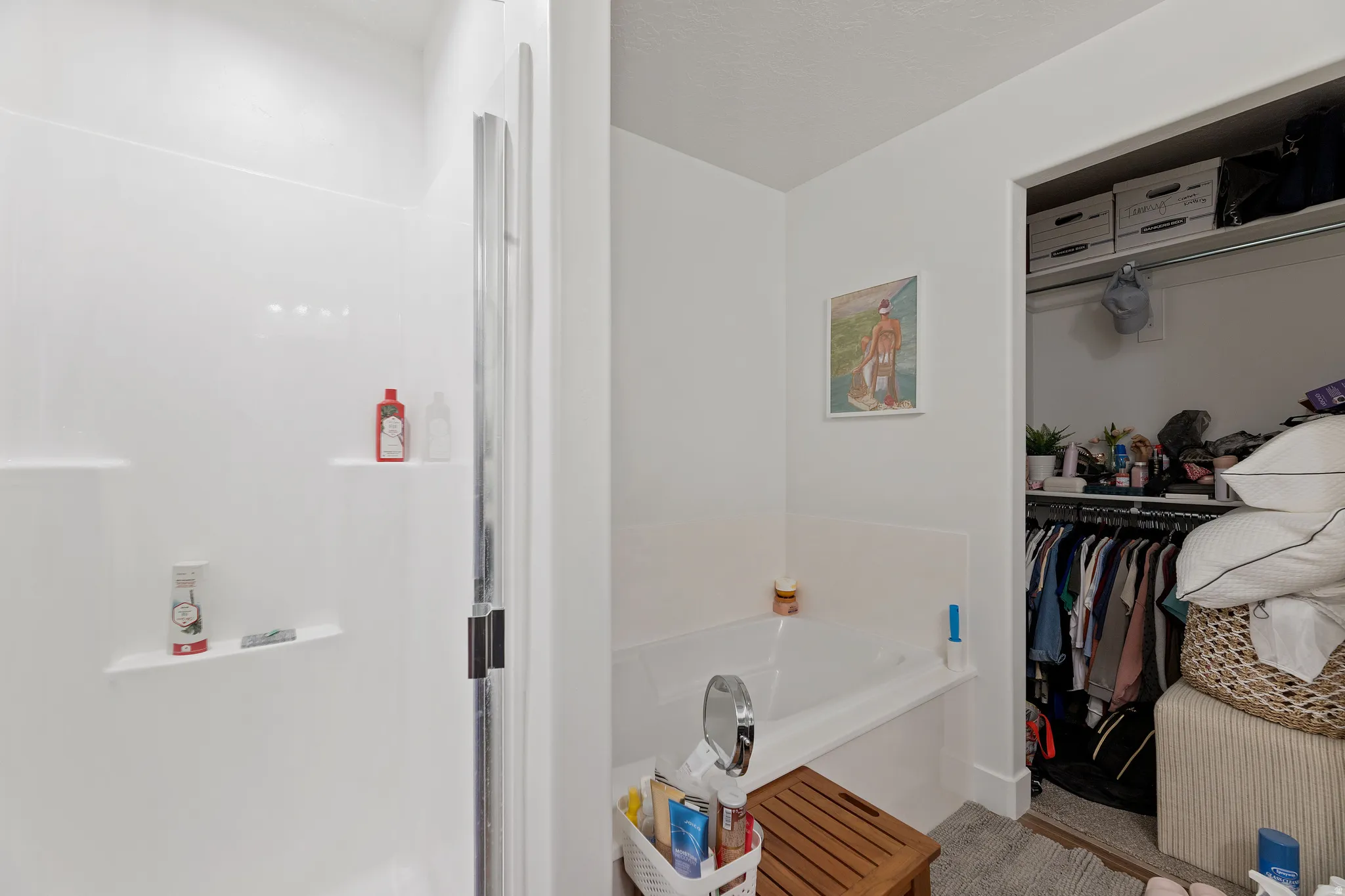 White shower enclosure with built-in shelving, glass shower door, and an adjacent built-in bathtub