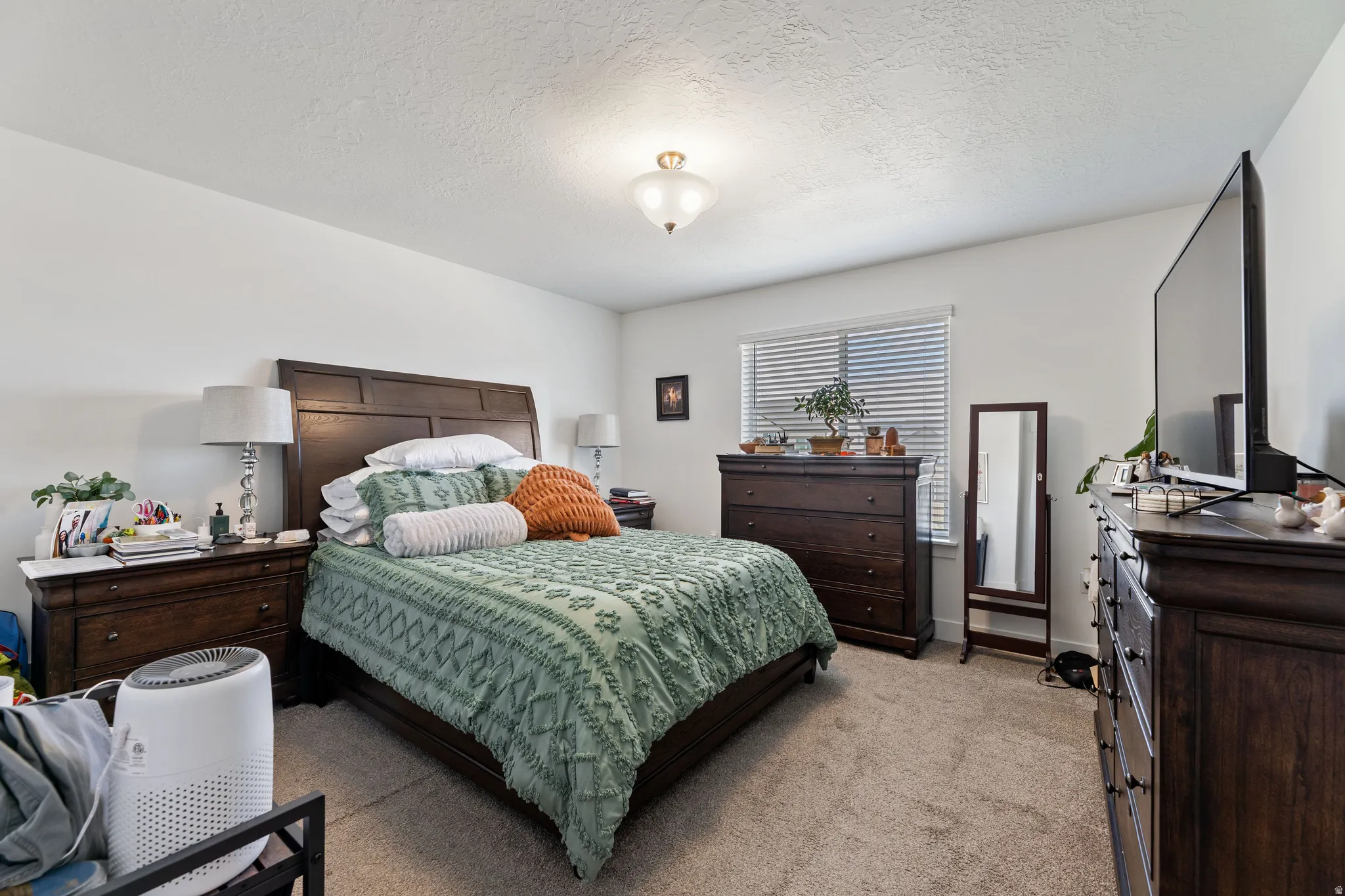 Carpeted bedroom with a single window featuring horizontal blinds