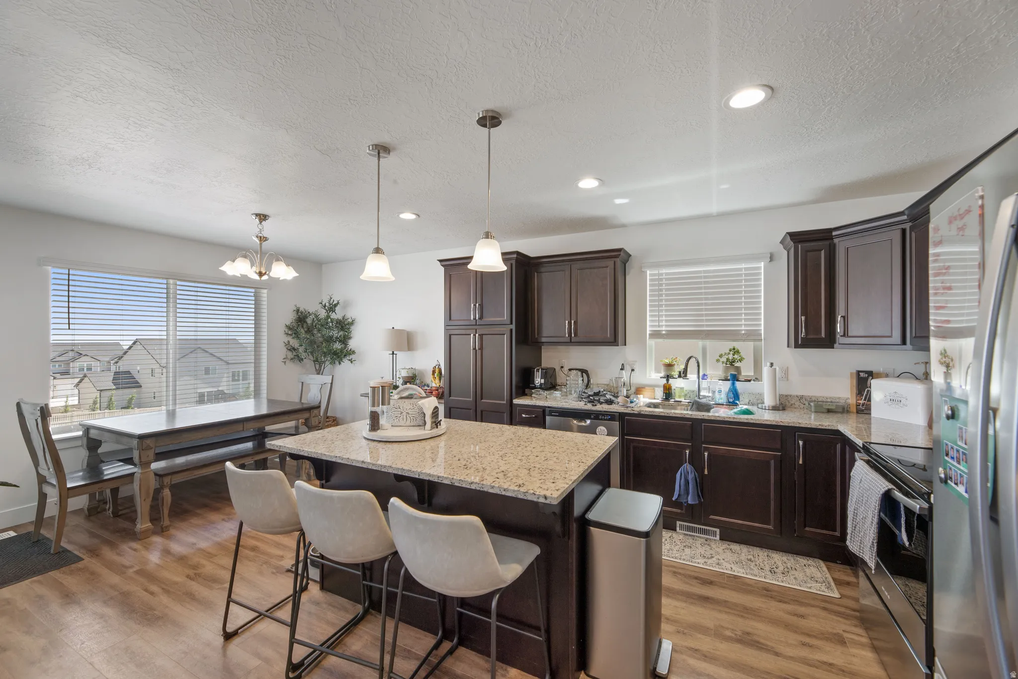 Open-concept kitchen featuring dark wood cabinetry, granite countertops, and wood-finish flooring