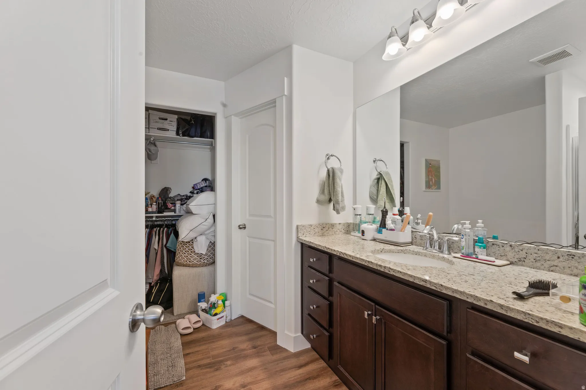 Bathroom with a large vanity featuring a light-colored speckled countertop, an undermount sink, and dark wood-finish cabinetry