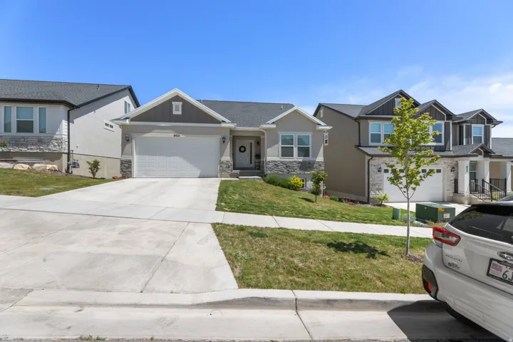 Modern single-story residence featuring a two-car garage, stone and stucco exterior, and a manicured front lawn