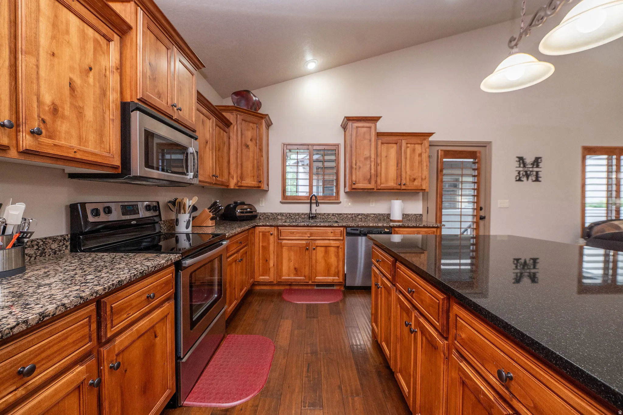 Full view of the kitchen work zone, with stainless range, microwave, dishwasher, and an abundance of counter space. The open sight line into the living areas makes this kitchen the true heart of the home.