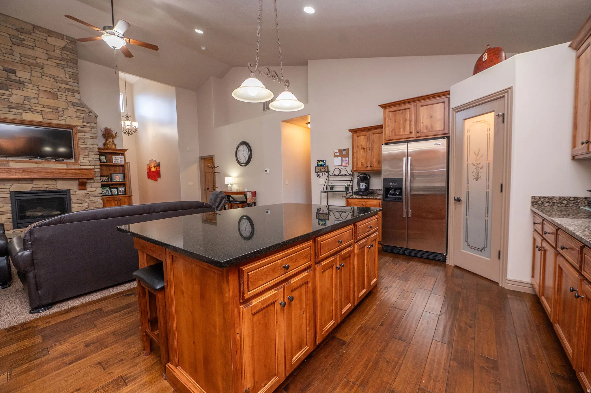 Perfect shot showing the seamless flow from kitchen island to living room and stone fireplace beyond. This is exactly the open layout buyers are looking for.