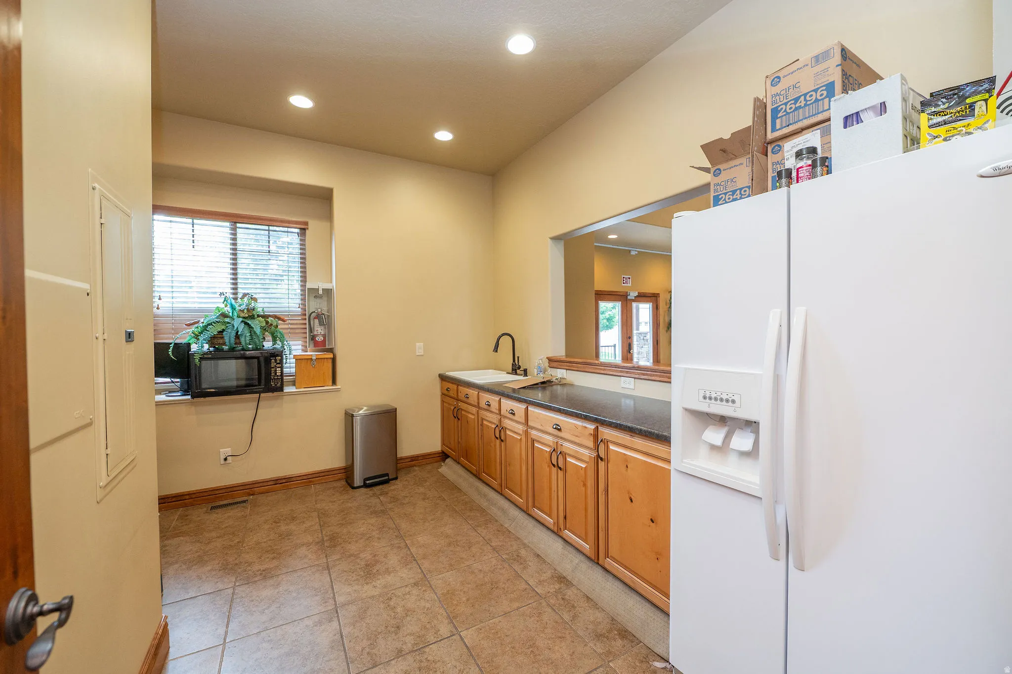 Clubhouse includes a functional kitchen area with knotty alder cabinetry, dark countertops, refrigerator, microwave, and tile flooring. Perfect for community events and gatherings.