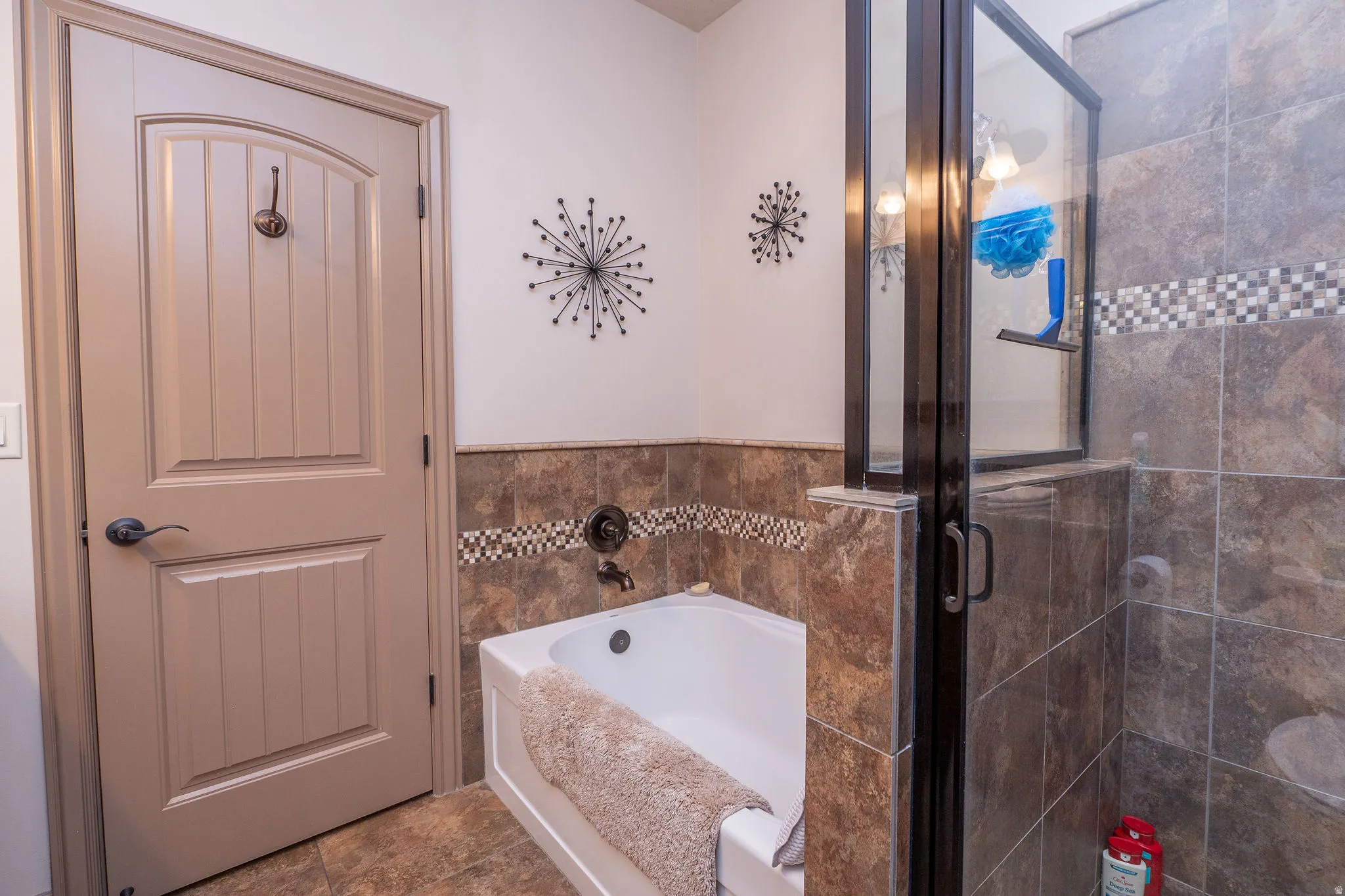 Primary bath features both a soaking tub with tile surround and mosaic accent band, plus a separate glass-door walk-in shower. Oil-rubbed bronze fixtures throughout tie it all together.