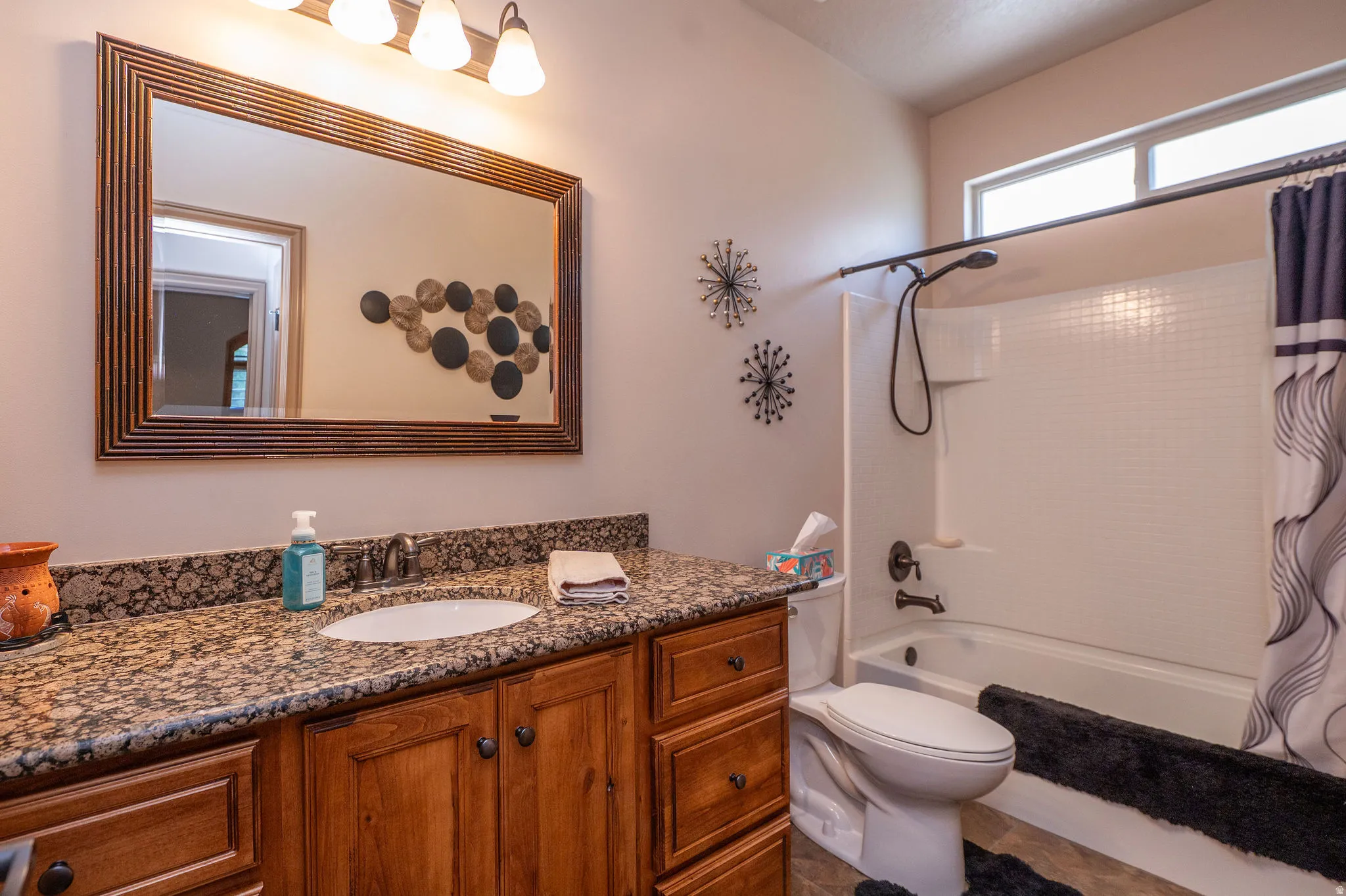Well-appointed full bath with rich knotty alder cabinetry, granite countertop, framed mirror, and tub/shower combo. Clean, functional, and full of character.