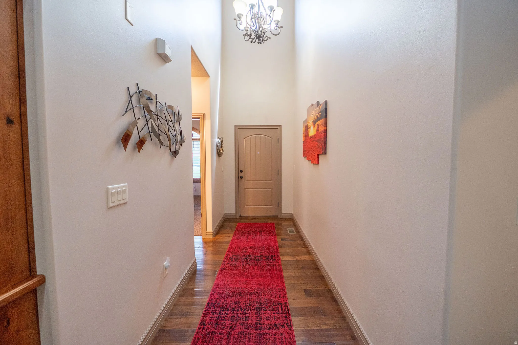 Another look at this impressive entry corridor showcasing the height of those ceilings, warm hardwood floors, and a bold front door that makes a statement from the moment you arrive.