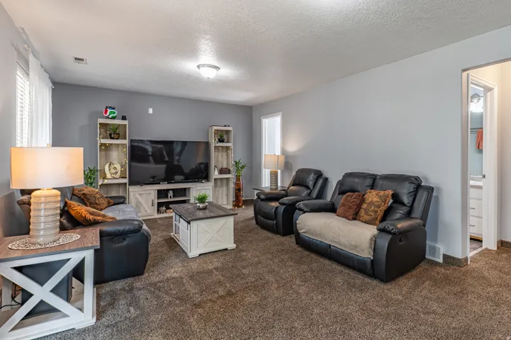 Spacious living area featuring neutral gray walls and plush carpeting throughout