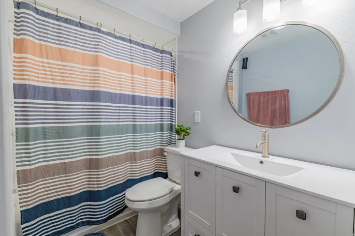 Bathroom featuring a white vanity with integrated sink, brushed nickel faucet, and a large circular mirror with a coordinating frame