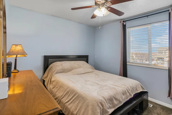 Bedroom featuring a large window with blinds, a ceiling fan with light fixture, and wood-finish flooring