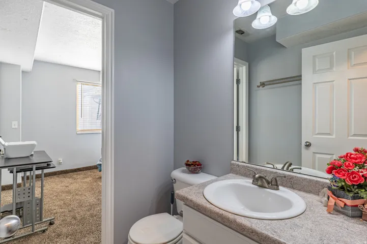 Bathroom featuring a vanity with an integrated sink, a speckled countertop, and a built-in mirror with overhead lighting