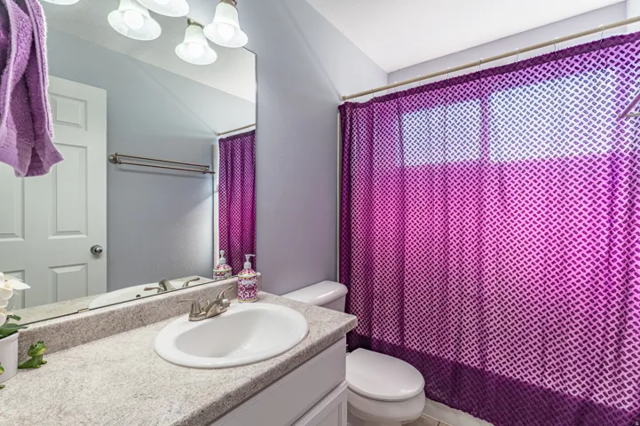 Bathroom featuring a single vanity with an integrated sink, laminate countertop, and a vanity mirror