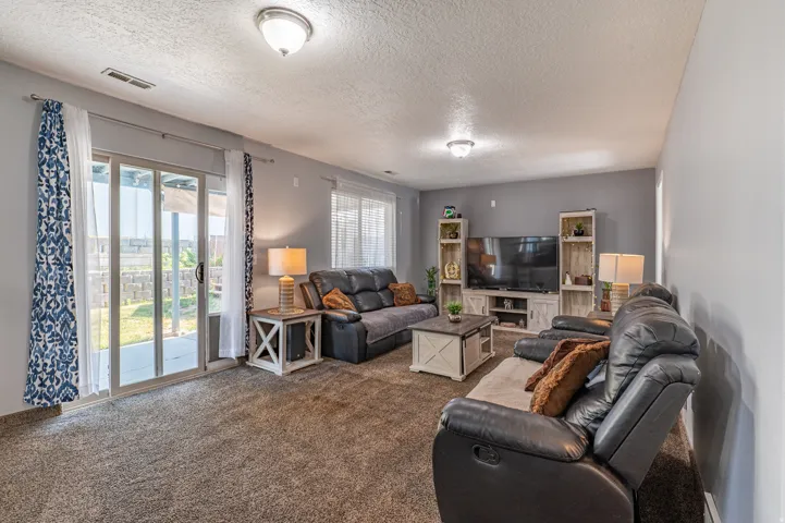 Living area featuring plush carpeting, sliding glass doors to the exterior, recessed lighting, and ample wall space