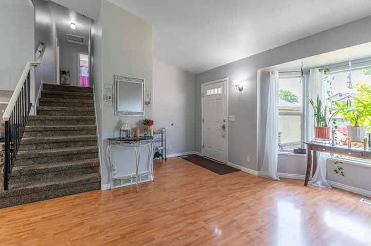Entryway featuring wood-finish flooring, a carpeted staircase with a black metal railing, and a multi-pane front door