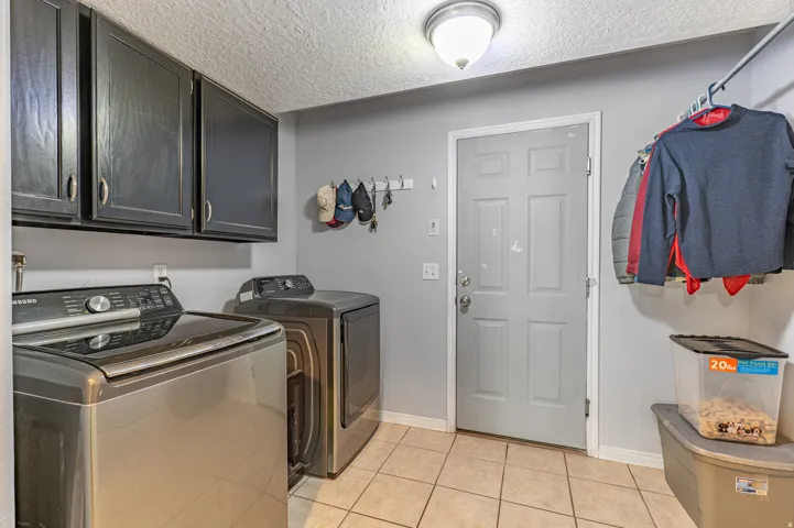 Dedicated utility room featuring upper cabinetry, a built-in hanging rack, light gray wall paint, and ceramic tile flooring