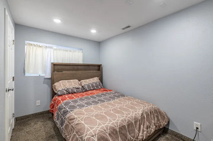 Carpeted room featuring light blue walls, recessed ceiling lighting, and a window with white curtains