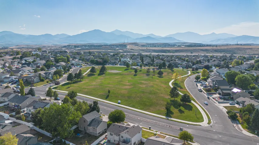 Expansive neighborhood park featuring a winding paved path, mature trees, and open green space