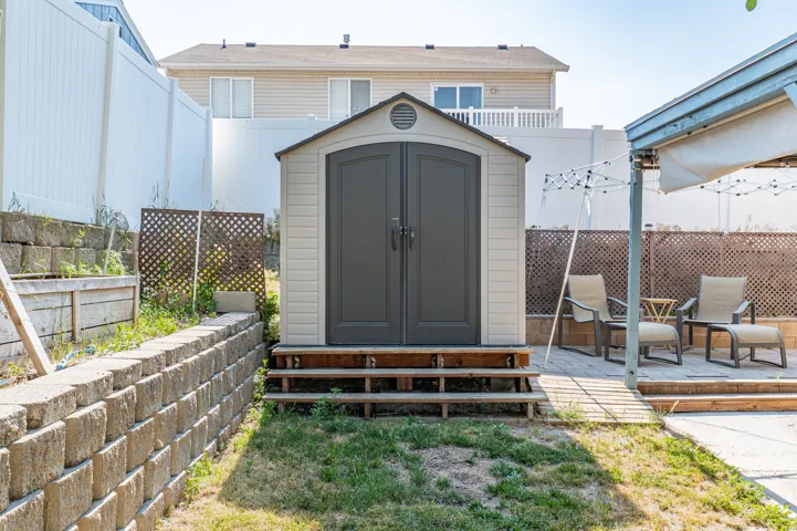 Outdoor storage shed with dual gray doors and a light beige siding