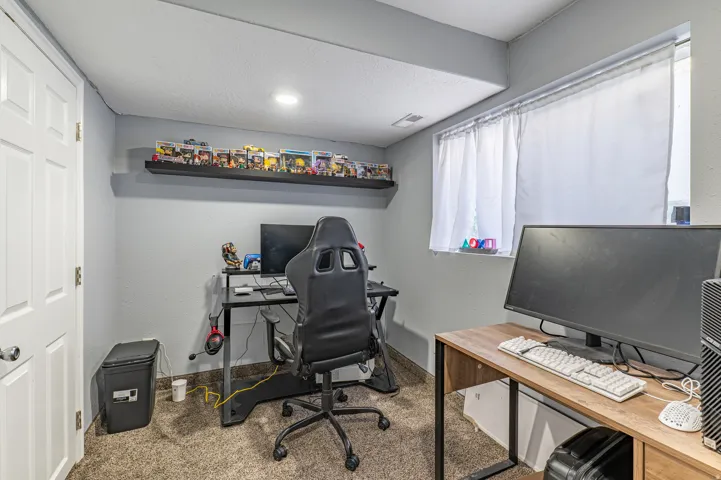 Carpeted room featuring light gray walls, a built-in wall shelf, recessed lighting, and a window with white curtains