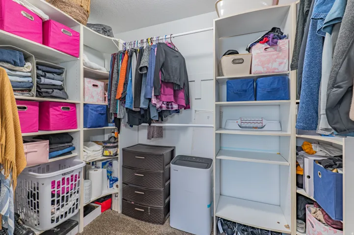 Walk-in closet featuring extensive built-in shelving, multiple hanging rods, and corner shelving units