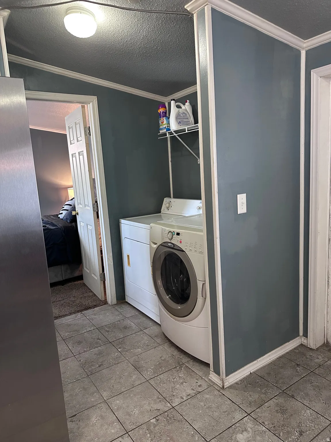 Dedicated utility area featuring tile flooring, a built-in wire shelf, and crown molding accents