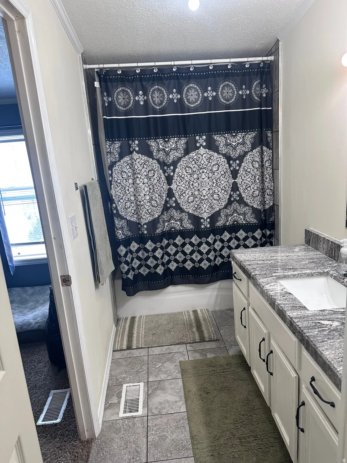 Bathroom featuring a single-sink vanity with white cabinetry, dark hardware, and a stone-finish countertop