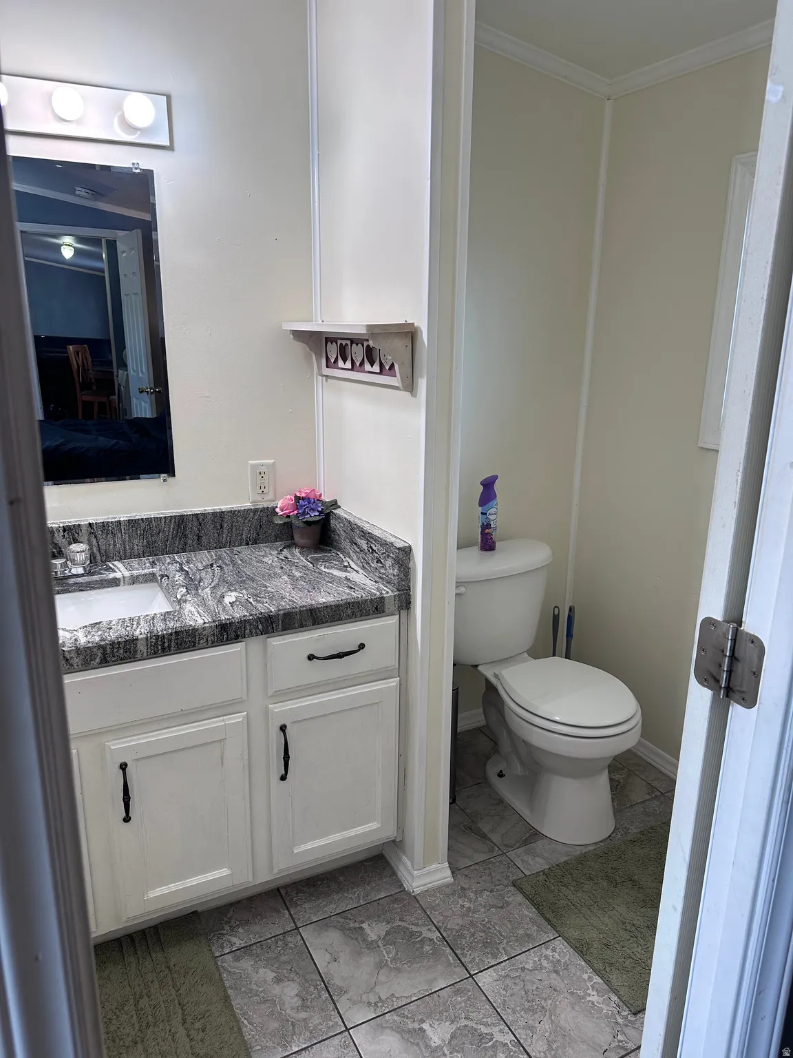 Bathroom featuring a white vanity with dark hardware, a grey patterned countertop, and an integrated white sink