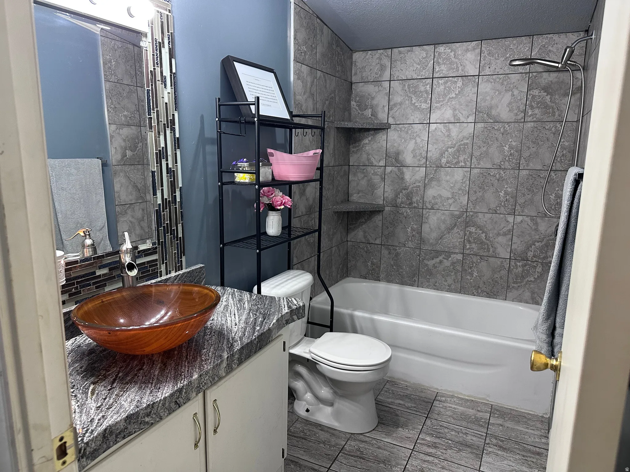 Bathroom featuring a glass vessel sink, speckled countertop, and subway tile backsplash